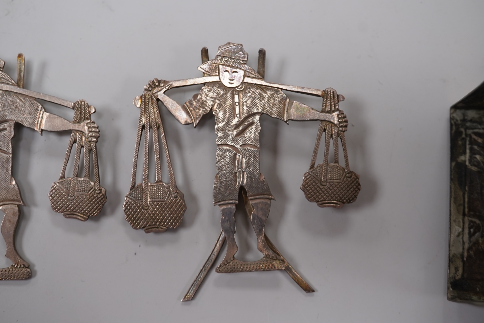 A Chinese Export white metal matchbox holder, with Chinese character mark stamp, embossed and engraved with dragon and prunus, 60mm and a pair of white metal figural menu holders, unmarked.